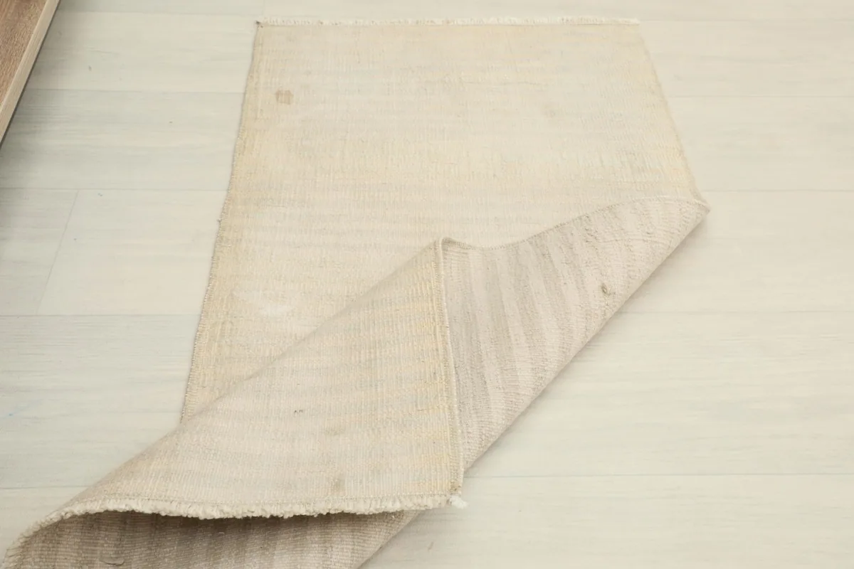 Partial fold of the rug, showing its flexibility and the uniform backing structure.