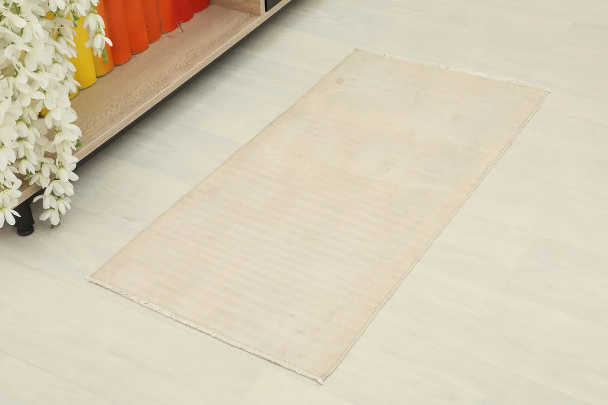 Overhead view of the beige doormat, highlighting its rectangular shape and subtle stripes.