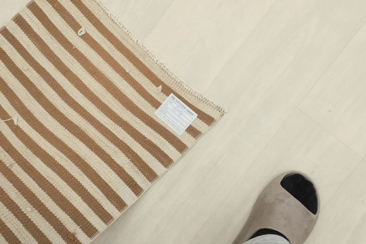 Rug next to a foot for scale, showing the doormat size and label on the back