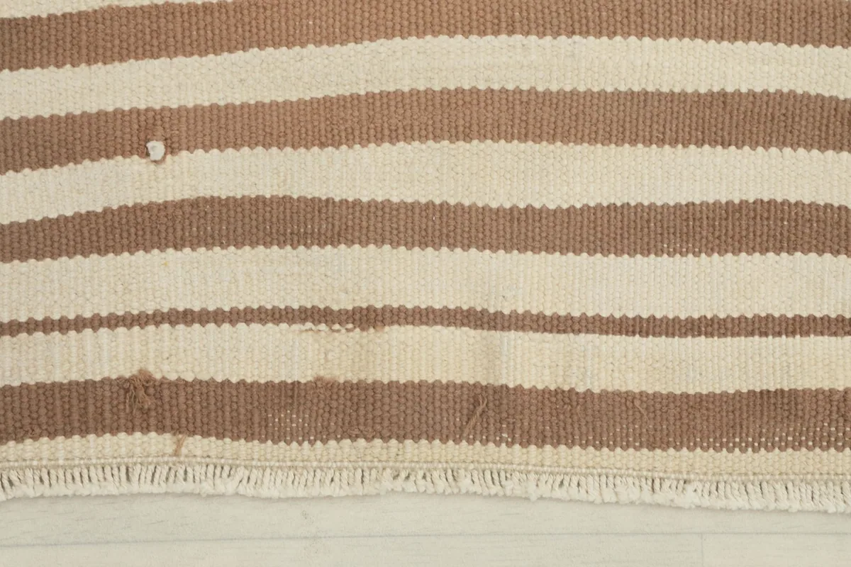 Close-up detail of the tan and ivory stripes and fringe, showing minor wear