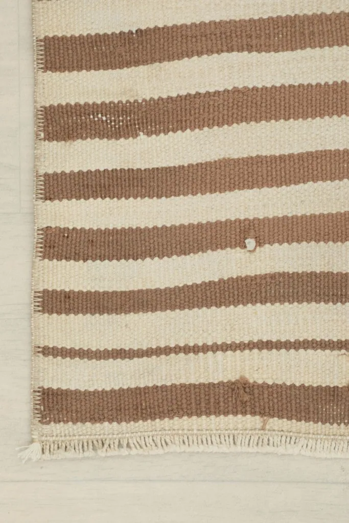 Corner detail of the rug, showing the stripes and edge finishing