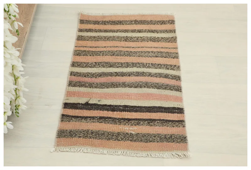 Full overhead view of the pink, brown, and beige striped vintage Anatolian doormat.