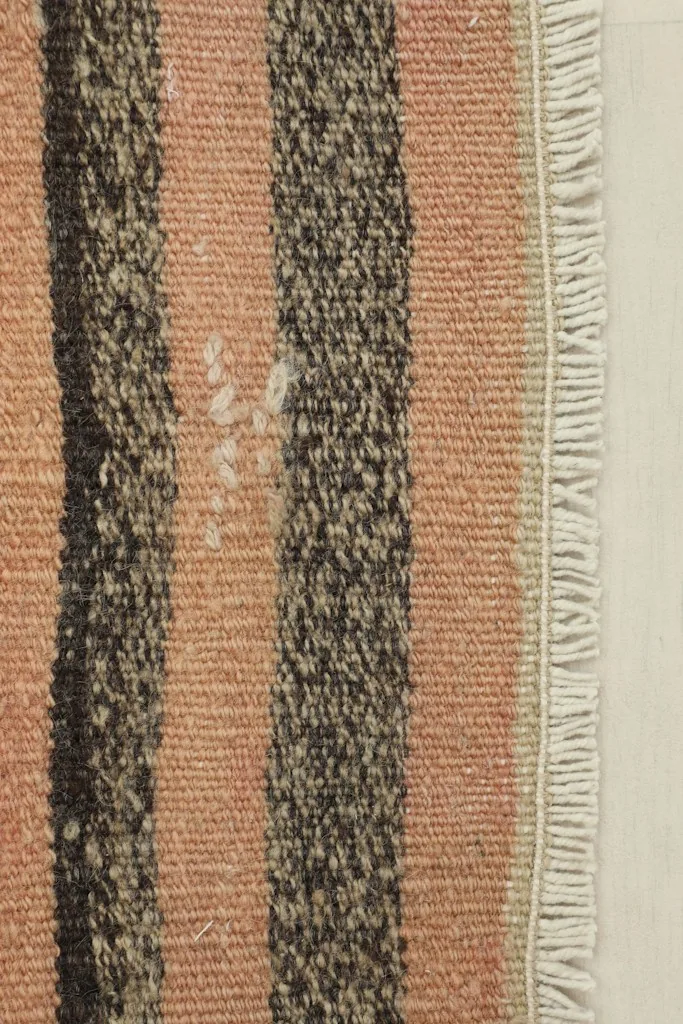 Close-up detail of the pink, brown, and beige stripes with visible wool pile texture and slight wear.