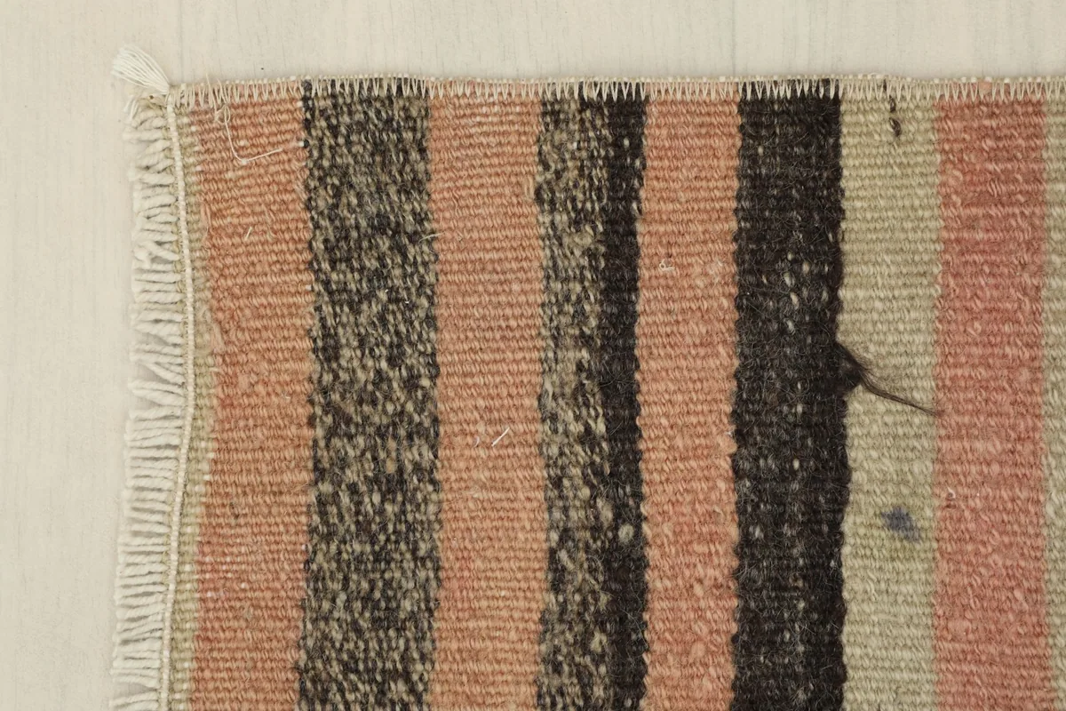 Detail view of the rug's edge and fringe, with a focus on the striped pattern meeting the border.