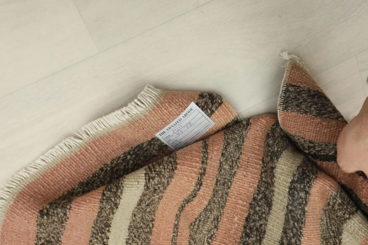 View of the rug's reverse side and label, demonstrating the hand-knotted cotton foundation.