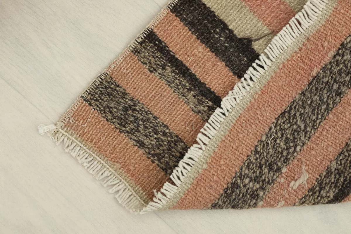 The rug folded back on itself, showing the thickness and flexibility of the vintage wool construction.