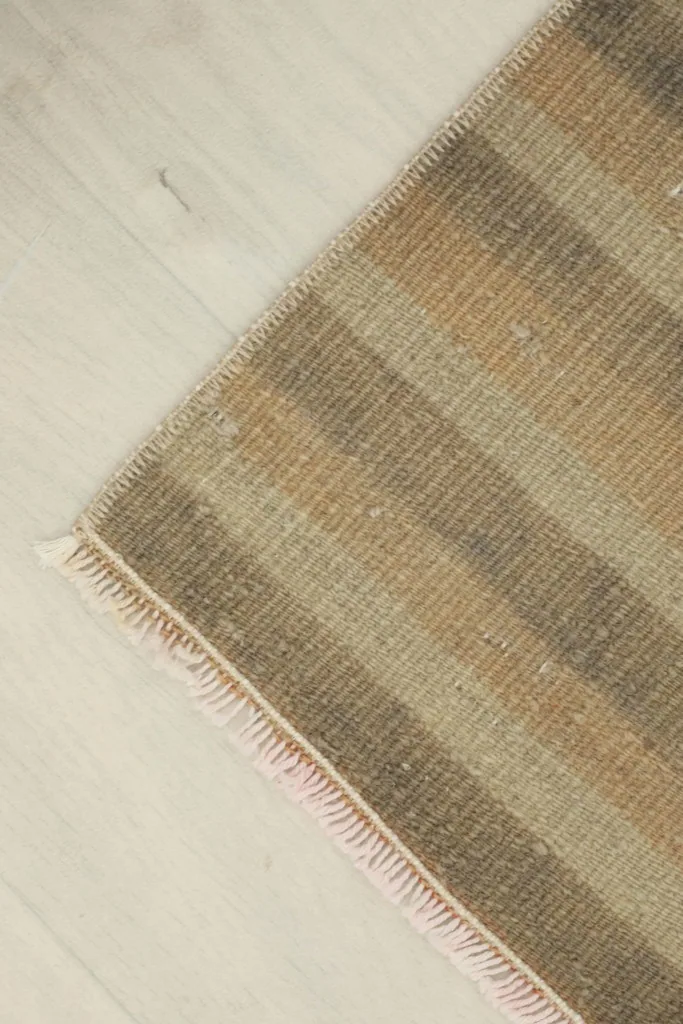 Angled view of the doormat's corner, showcasing the fringe and the striped pattern.