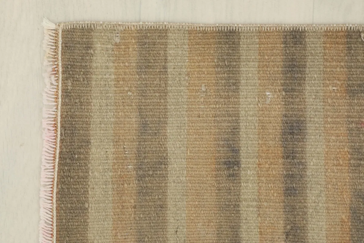 Corner detail showing the hand-knotted construction and the subtle color shifts in the stripes.