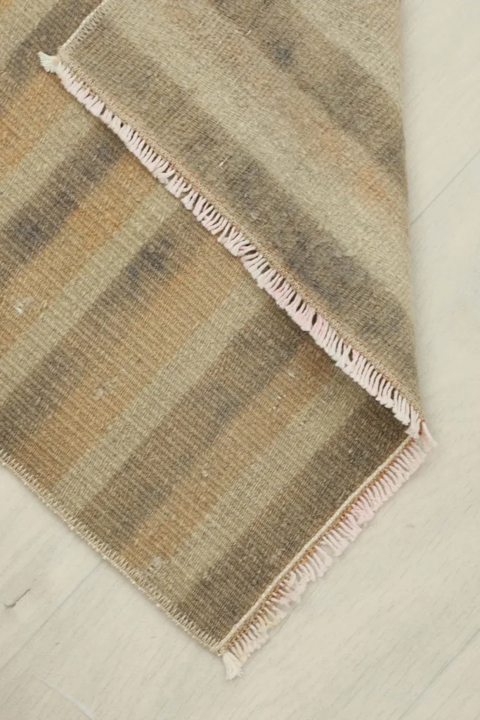 The doormat folded partially, revealing the thickness of the wool pile and the cotton foundation.
