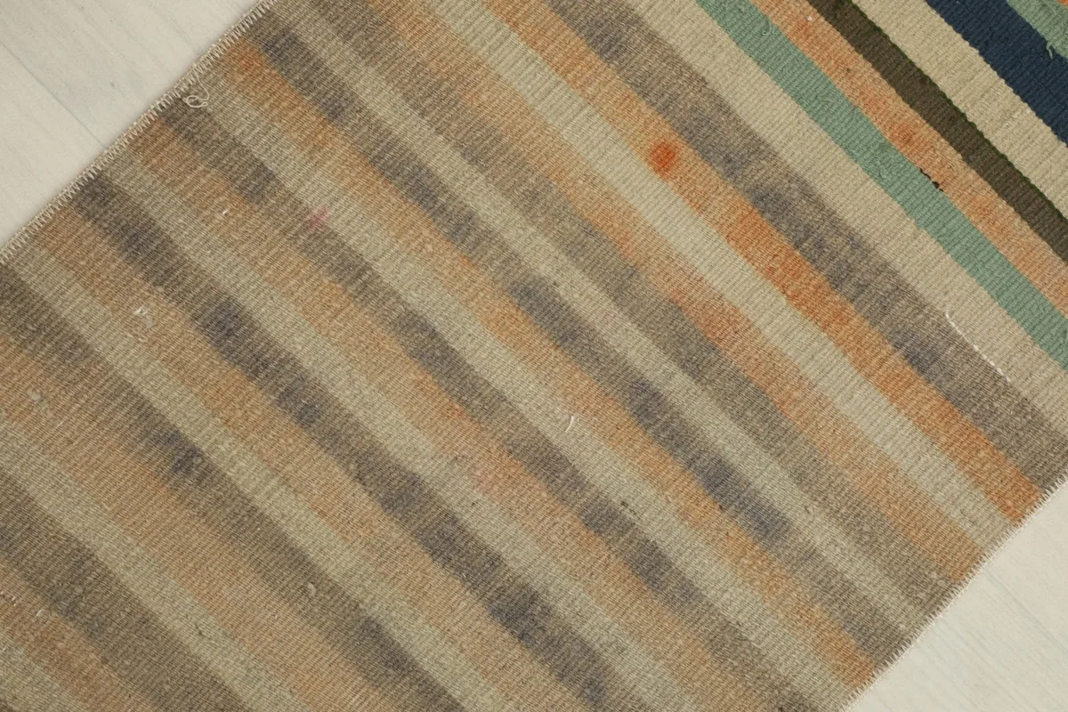 Overhead view from an angle, focusing on the blend of muted and vibrant stripes across the rug.