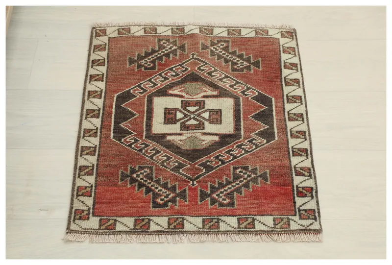 Full overhead view of the vintage red tribal geometric rug on a white background