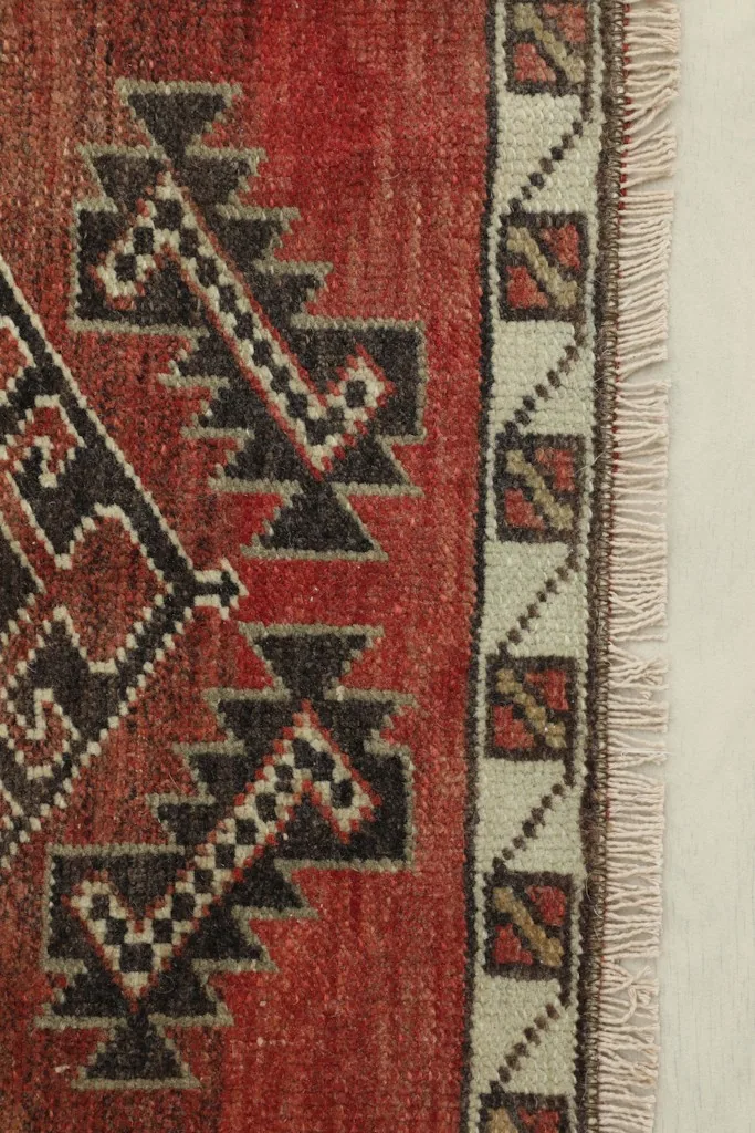 Close-up detail of the rug's border and a section of the red field with tribal motifs