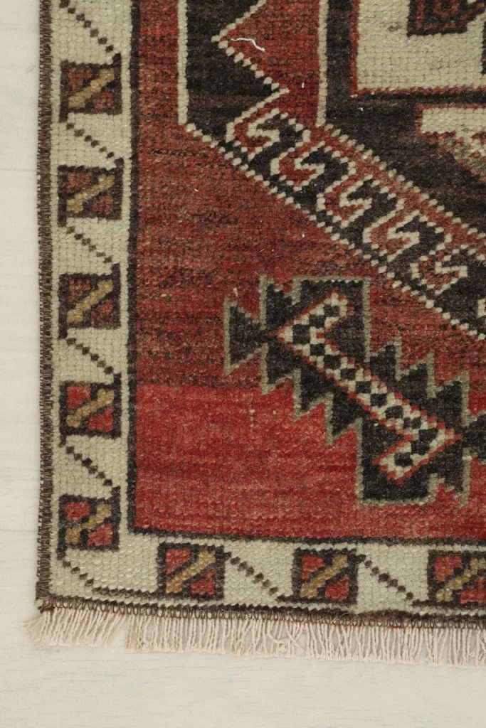 Close-up of the corner, showing the ivory border with small geometric patterns and fringe
