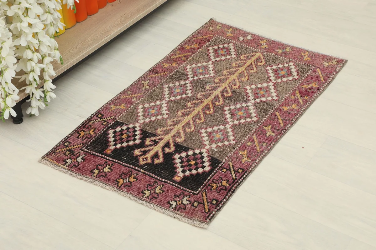 Angled view of the rose and brown vintage doormat on a light floor