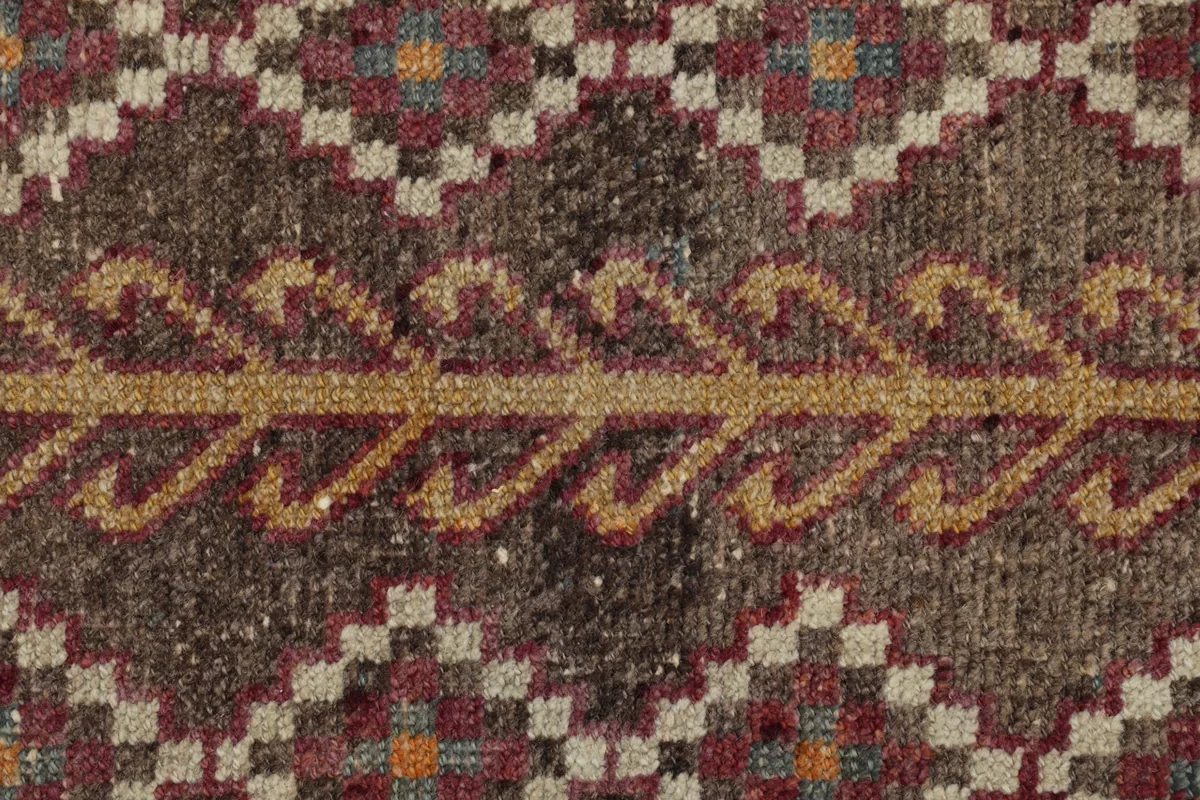 Close-up of the gold and orange accents within the brown field of the rug