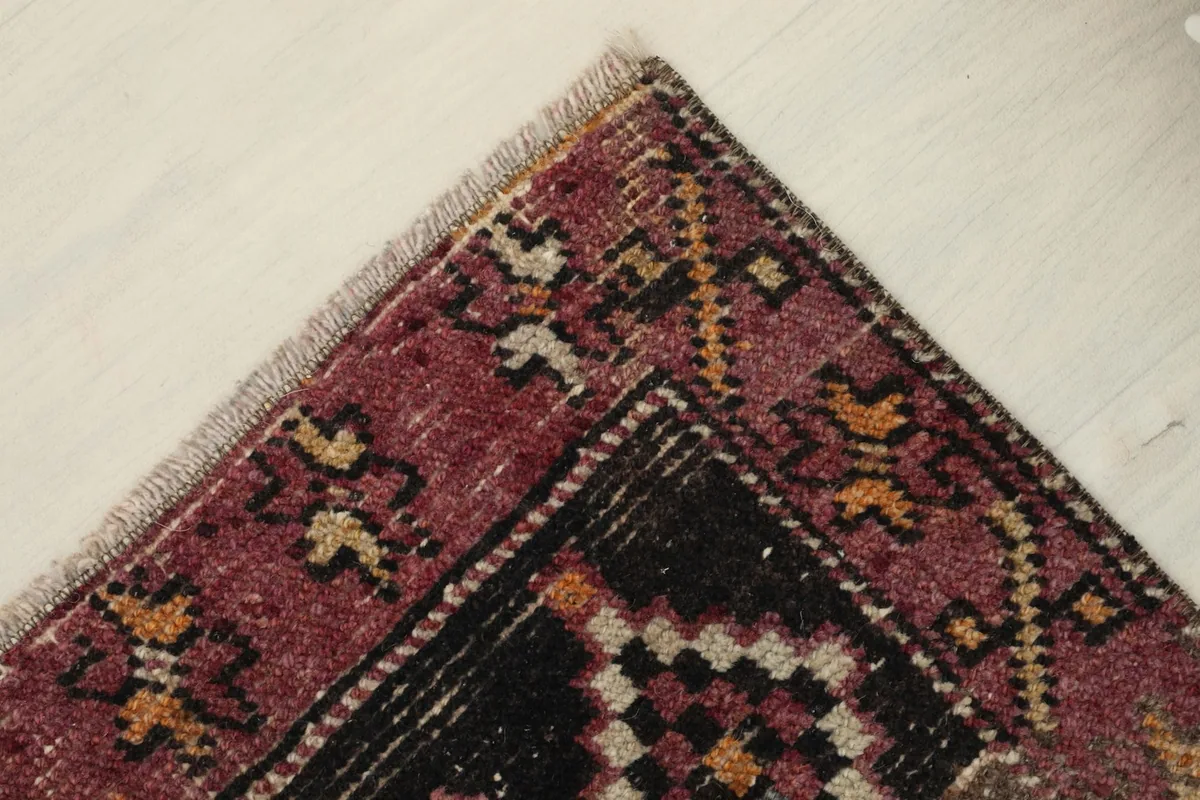 Corner detail showing the rose border and fringe of the hand-knotted rug