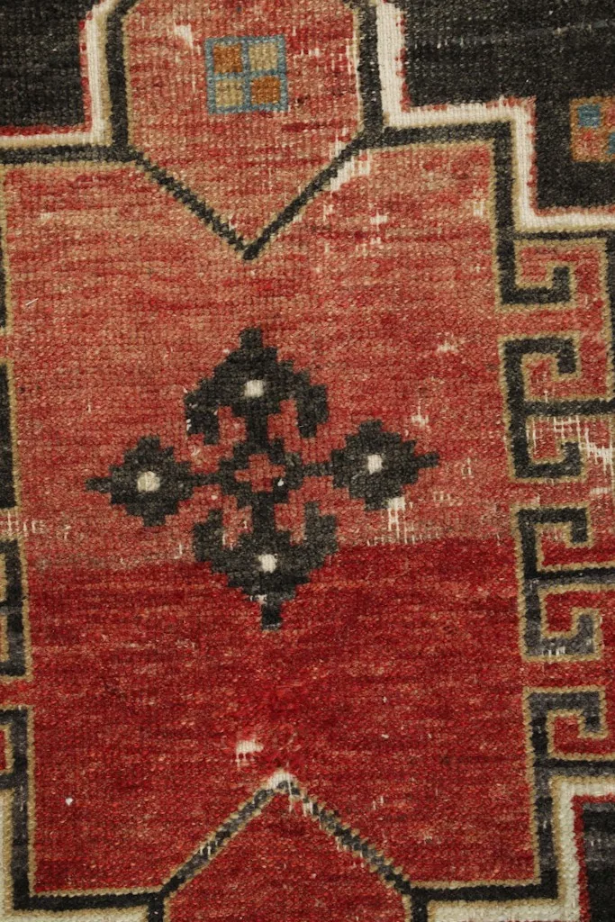 Close-up of the central motif within the rust field, showing the intricate hand-knotted details.