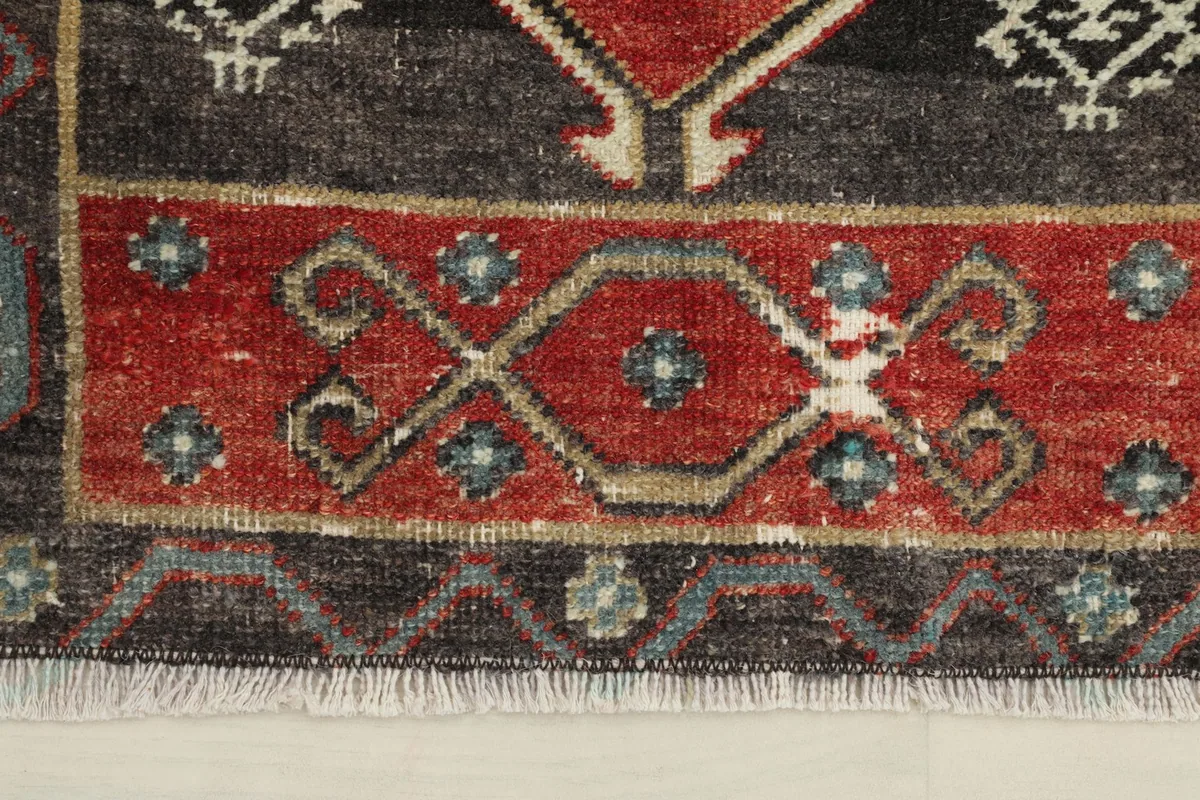 Close-up of the rug's border, highlighting the charcoal color and geometric patterns with blue accents.