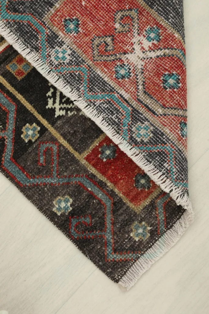 View of the rug folded to show the thickness and flexibility of the vintage hand-knotted wool.