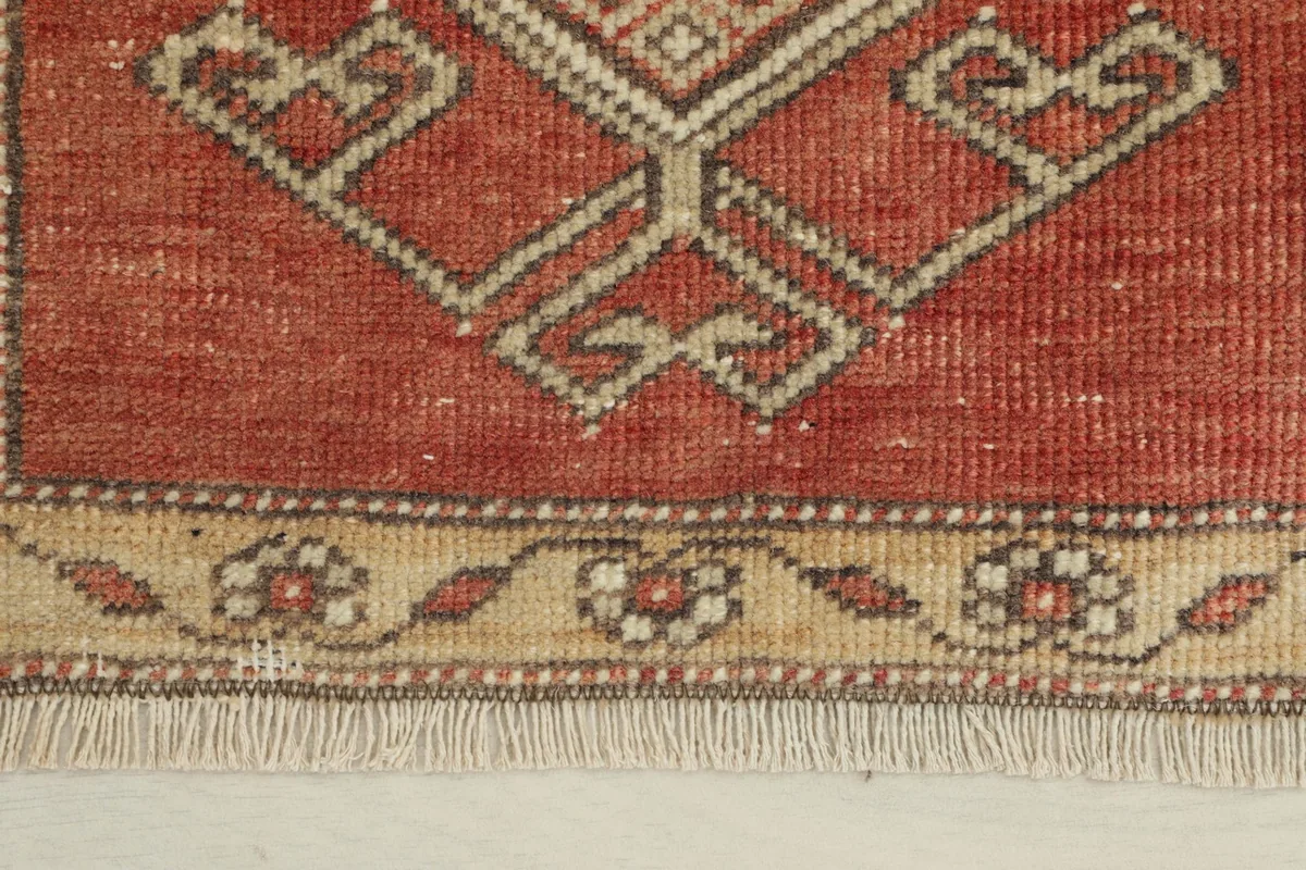 Close-up of the tan floral border and rust field with geometric motifs