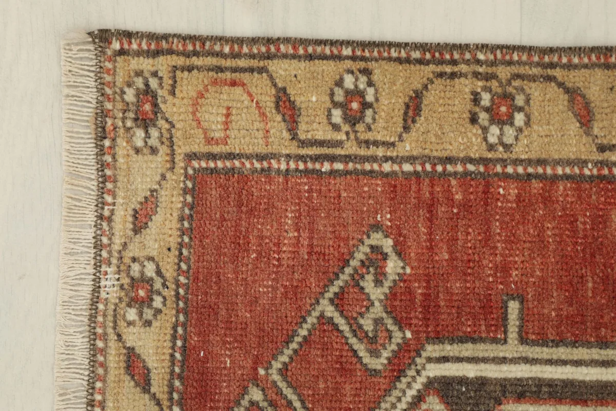 Corner detail showing the tan border with floral designs and fringe
