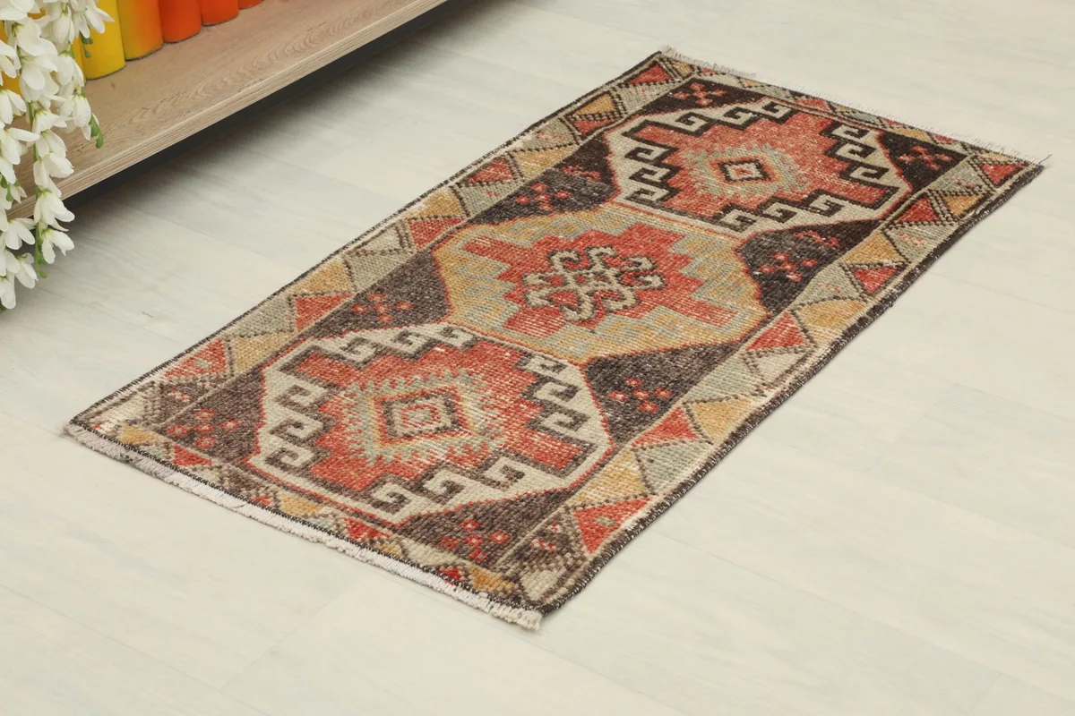 Angled top-down view of the hand-knotted wool doormat, showing its full length and geometric pattern.