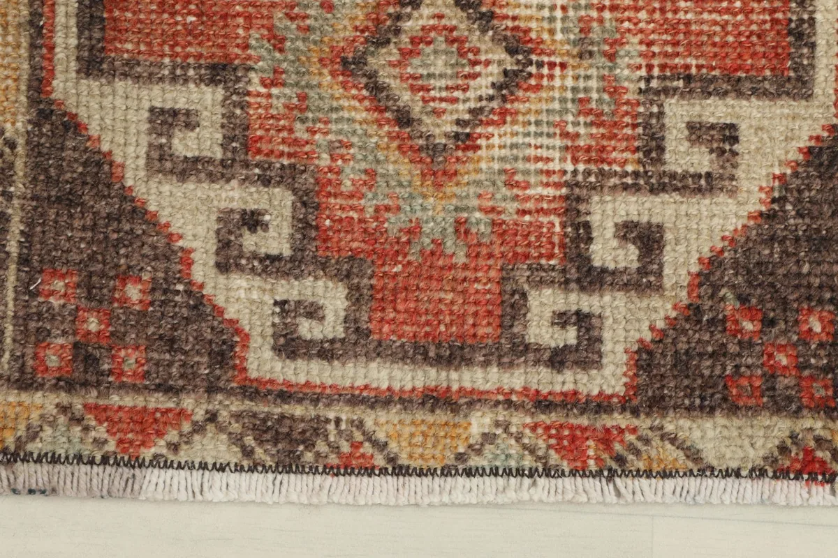 Close-up detail of the rust and beige geometric patterns and the low pile texture of the rug.
