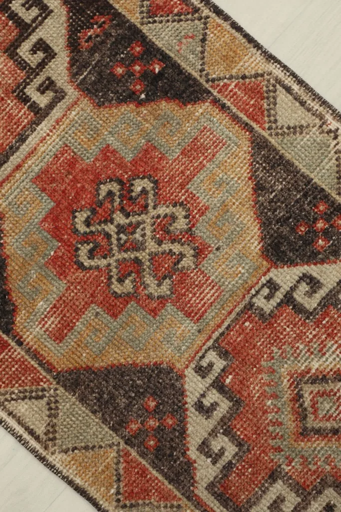 Overhead close-up showing the central medallion-like motif and surrounding tribal designs in rust, brown, and tan.
