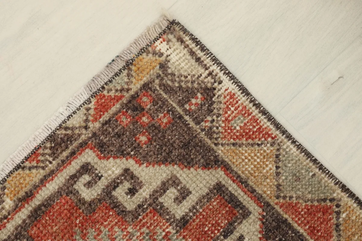 Corner detail of the vintage doormat, capturing the texture and the subtle color shifts from age.