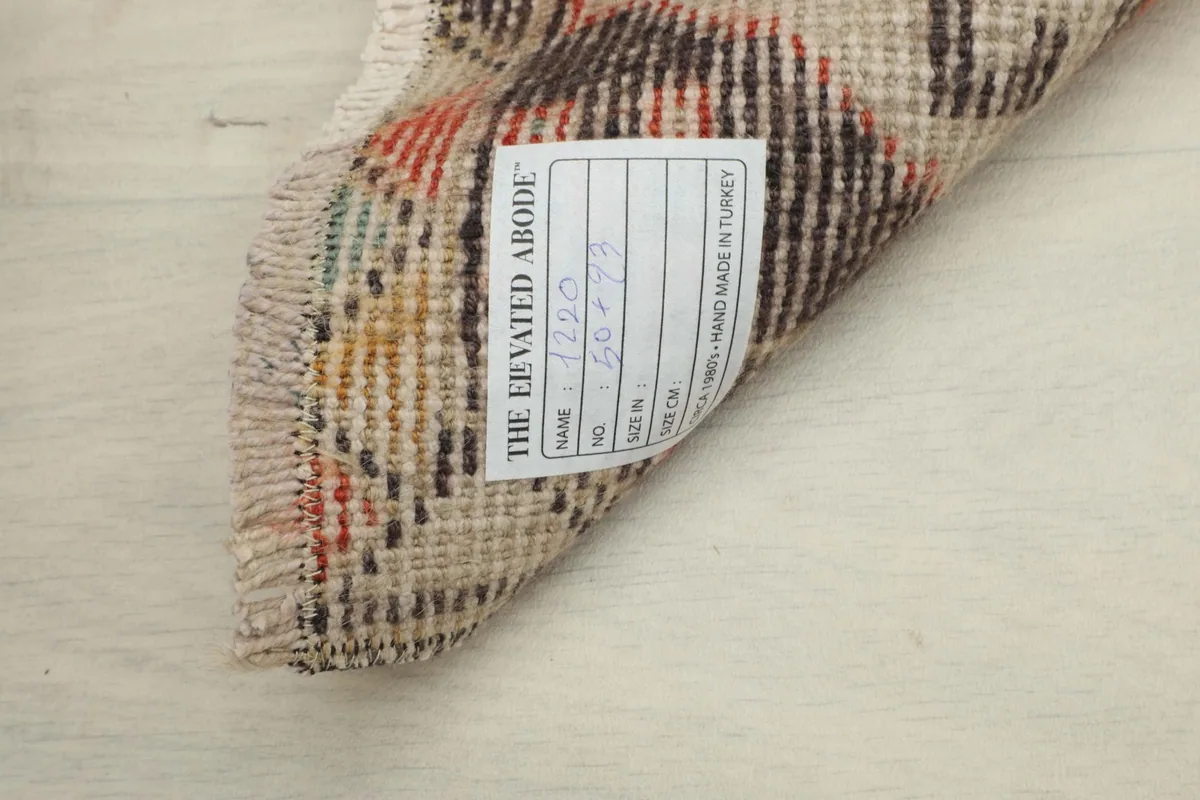 View of the back of the rug, showing the hand-knotted cotton foundation and the product label.