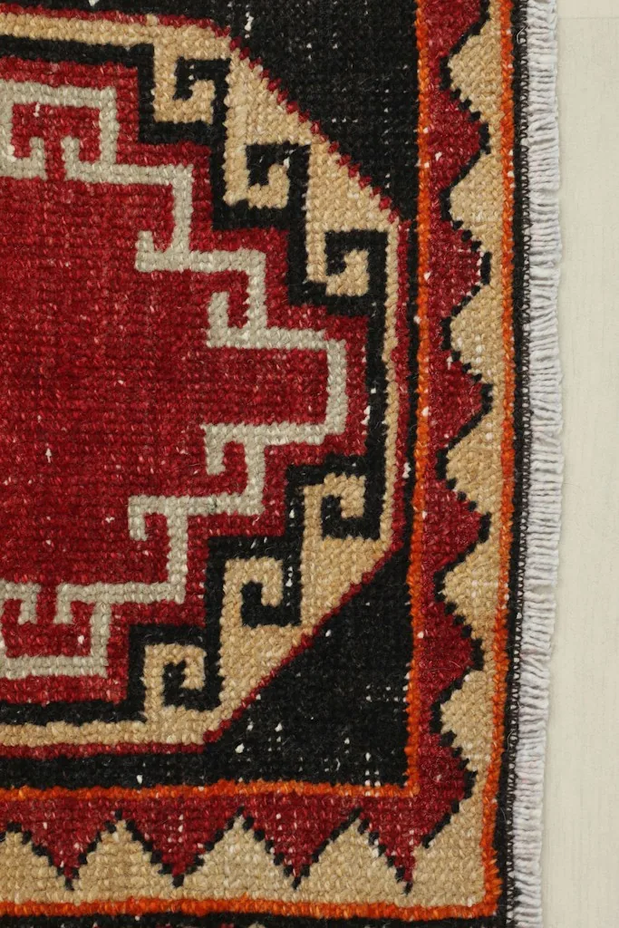 Close-up detail of the red and tan geometric patterns and black field
