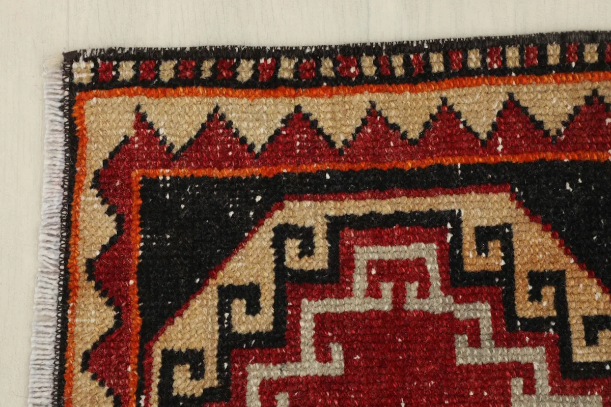 Corner detail showing the patterned border in red, tan, and orange tones