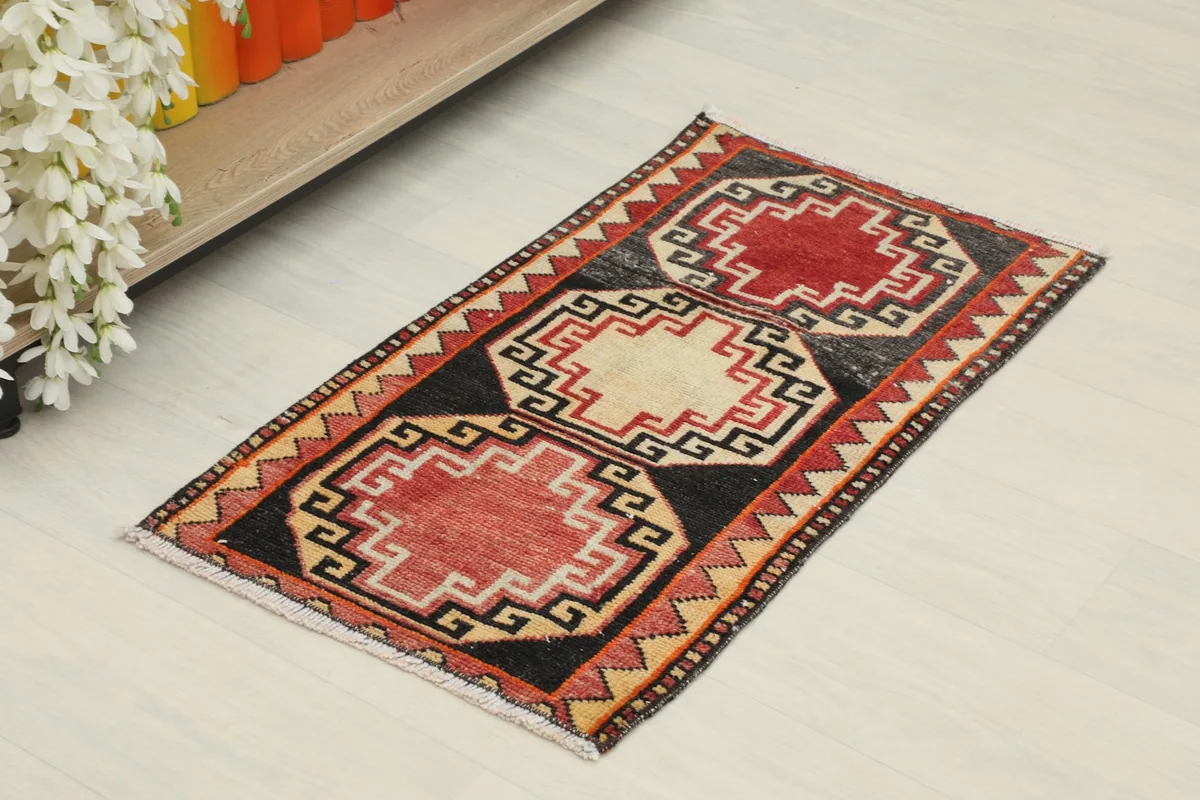 Angled view of the red and black tribal doormat, showing its full design and colors.