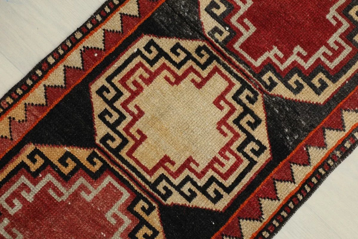 Detailed angled view of the central ivory medallion with red and black geometric borders.