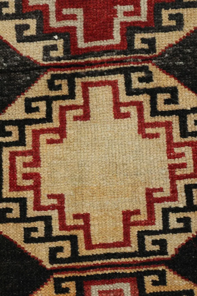 Overhead close-up of the ivory and red central geometric motif, highlighting knotting detail.