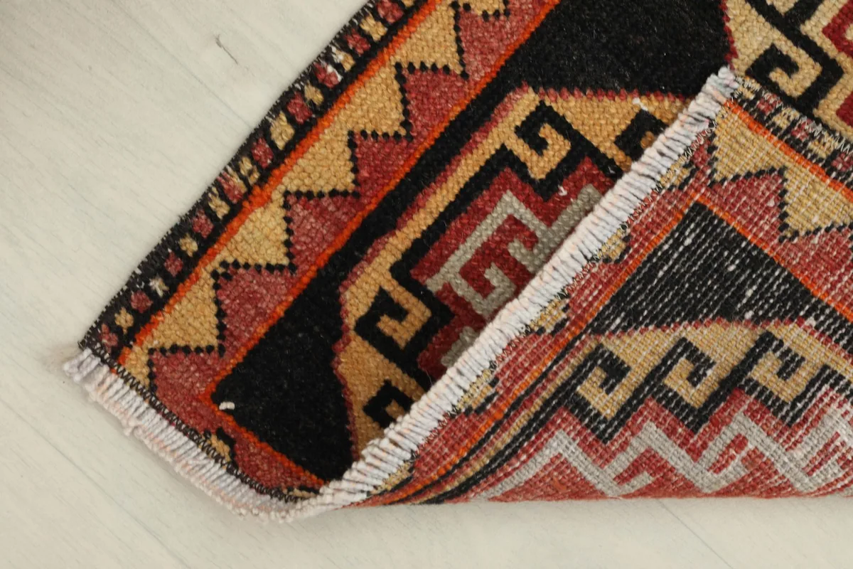 Rug partially folded, revealing the back of the hand-knotted wool pile on cotton foundation.