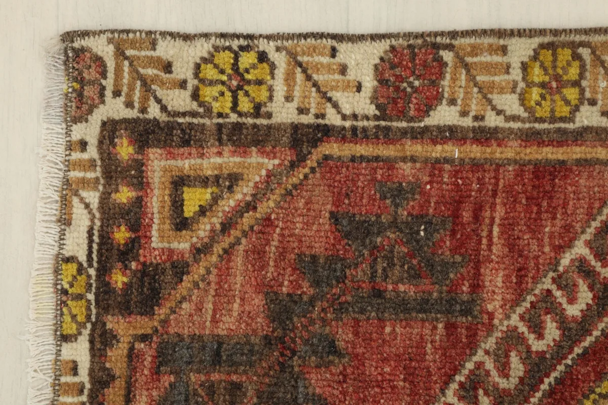 Detail of the beige border with gold and red floral motifs and the rug's edge.