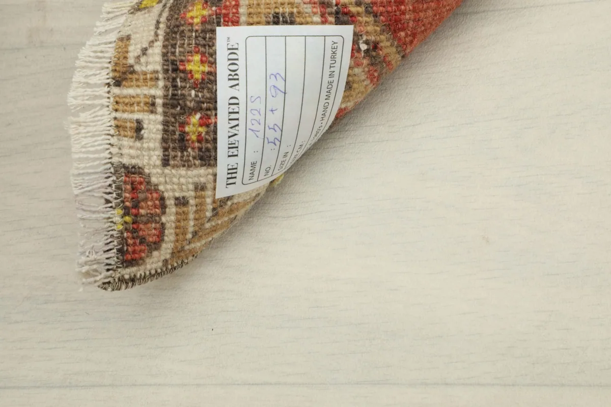 View of the rug's back, revealing the hand-knotted cotton foundation and care label.