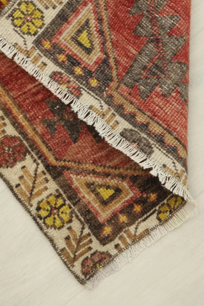 The rug partially folded, showing the flexibility and thickness of the vintage wool pile.