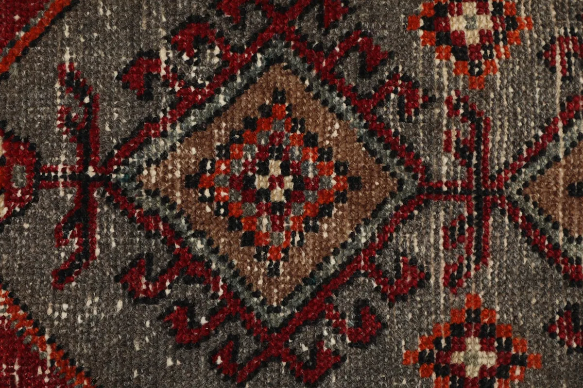 Detailed view of the intricate diamond and square motifs within the gray central panel of the rug.