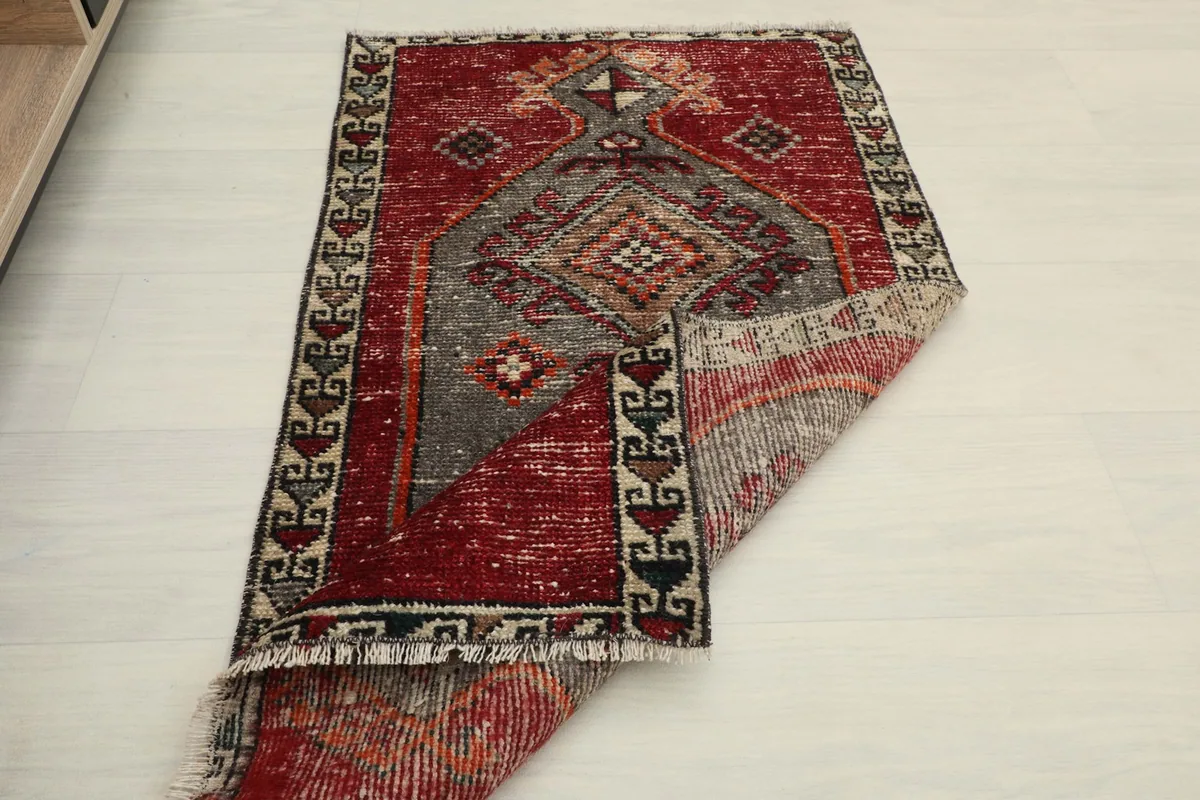 Angled view of the rug with one corner folded back, showing the back and front texture.