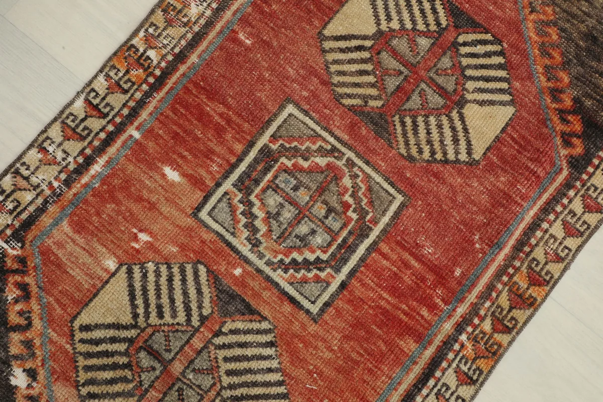 Angled close-up of the rug's rust field and central geometric motifs in charcoal, beige, and blue.