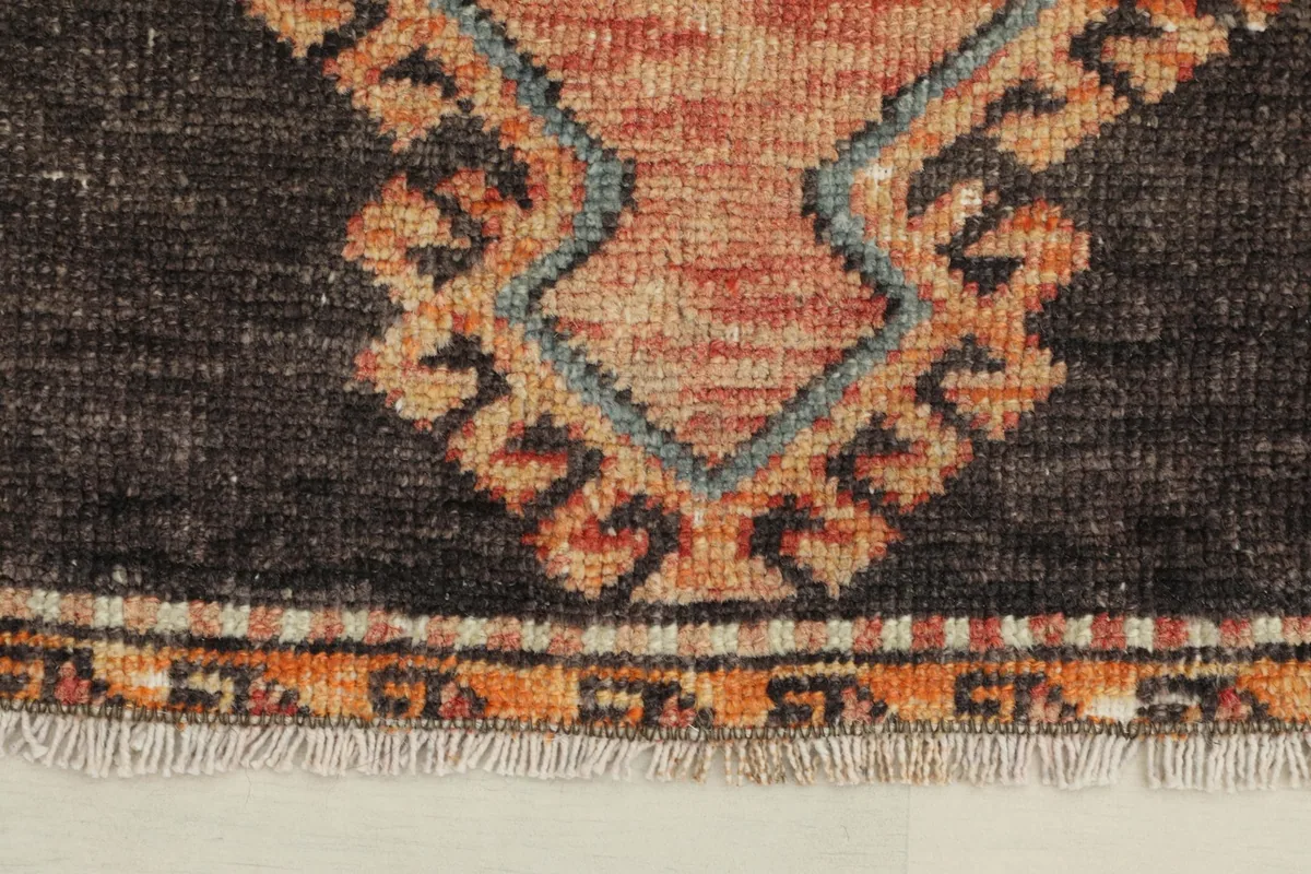 Close-up detail of the fringe and the orange and beige border pattern at the rug's end.
