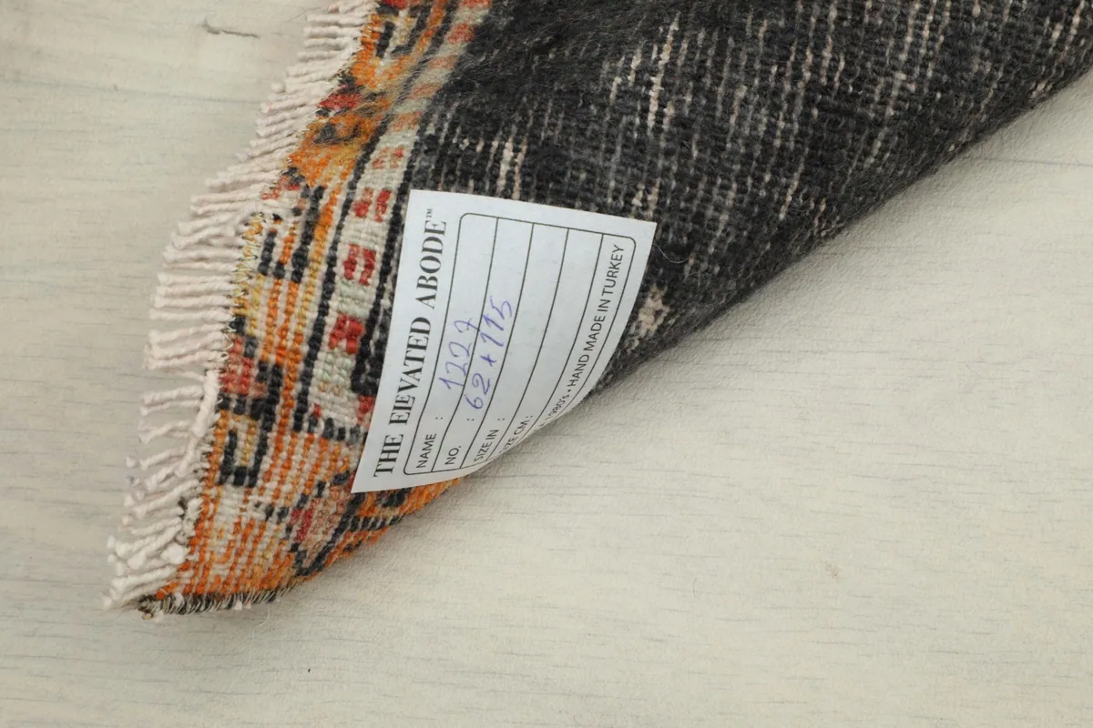 Close-up of the rug's back, showing the tight knotting and a label with the rug's dimensions.