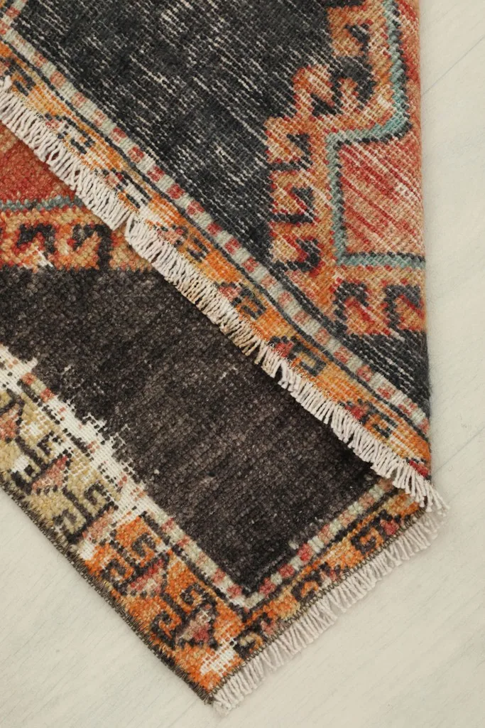A folded section of the rug, showing the reverse side, the cotton foundation, and the hand-knotted construction.