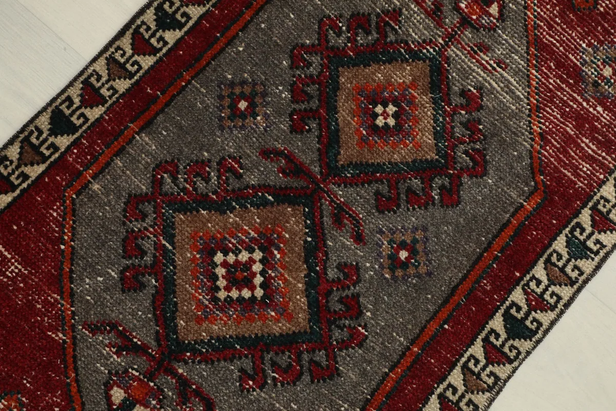 Detailed view of the central gray geometric pattern with brown and red accents, highlighting the hand-knotted wool pile.