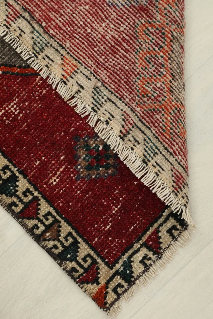Partial fold of the rug, revealing the reverse side and the woven cotton foundation.