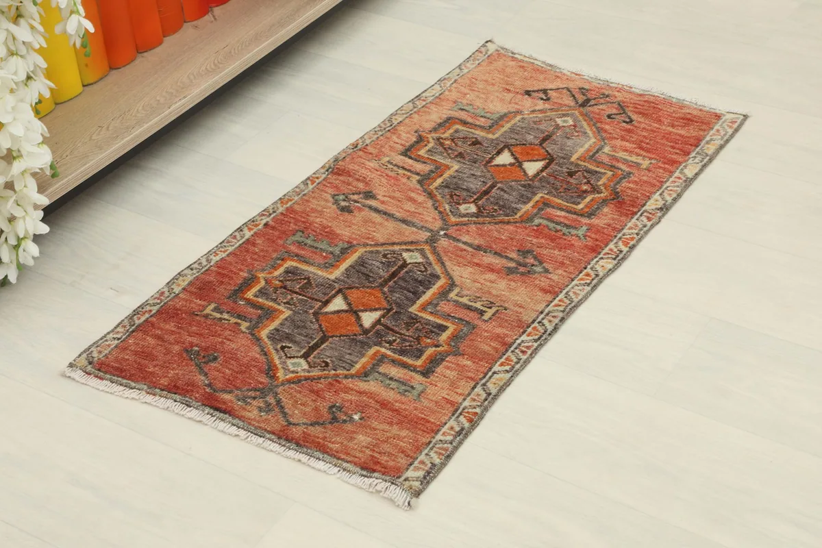 Angled view of the vintage Anatolian rug, highlighting its rust and charcoal geometric patterns and low pile.