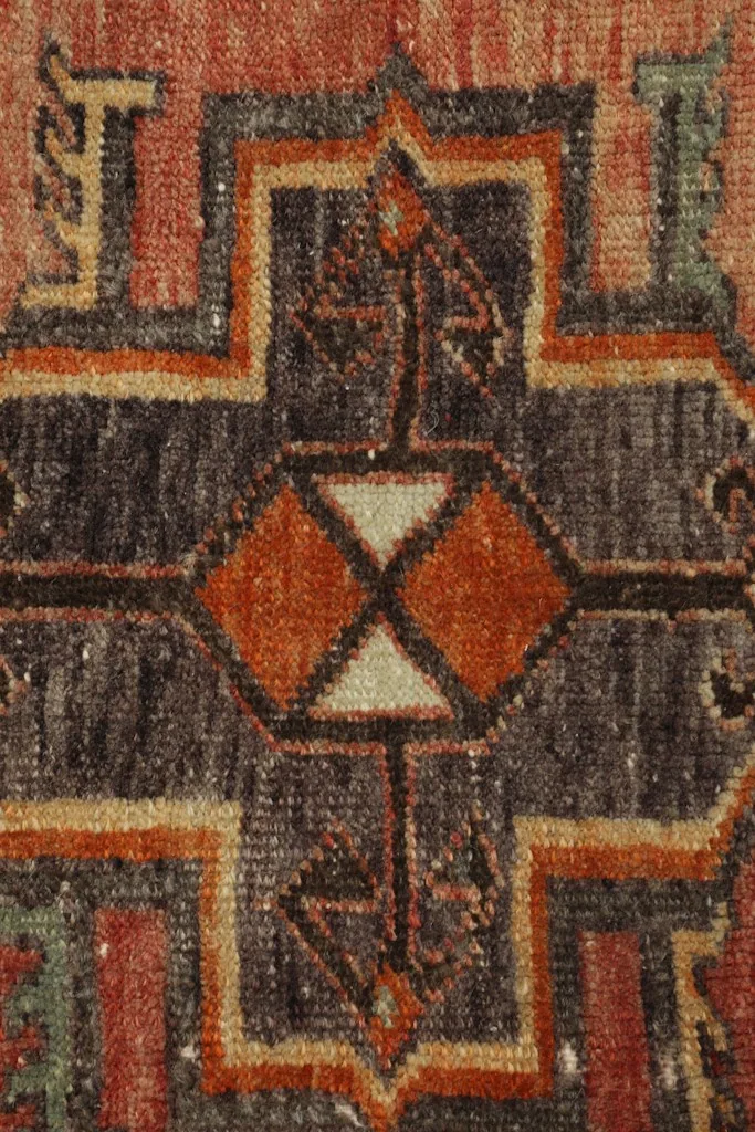 Detailed view of the central geometric medallion, featuring charcoal, orange, and beige elements.