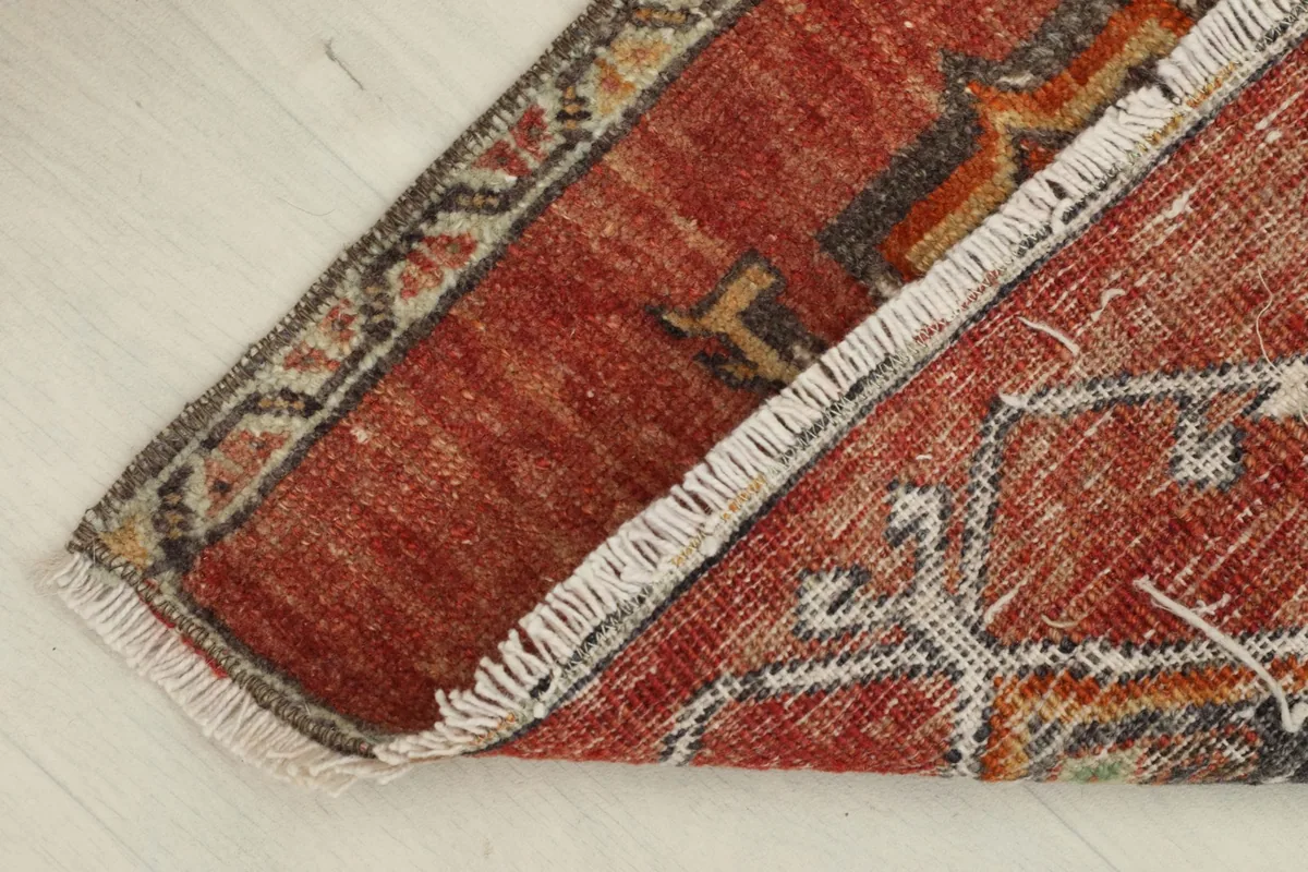 The rug partially folded, illustrating the flexibility and thickness of the vintage hand-knotted wool.